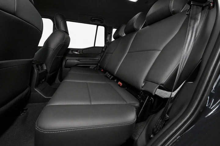Rear third-row leather seats in a black vehicle interior, showing the seat cushions, backrests, seatbelts, and door panels.