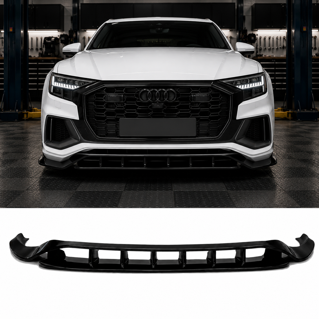 A glossy black front splitter lip valance spoiler shown below, with a white Audi Q7 with RS style grille above in a garage setting demonstrating its fitment.