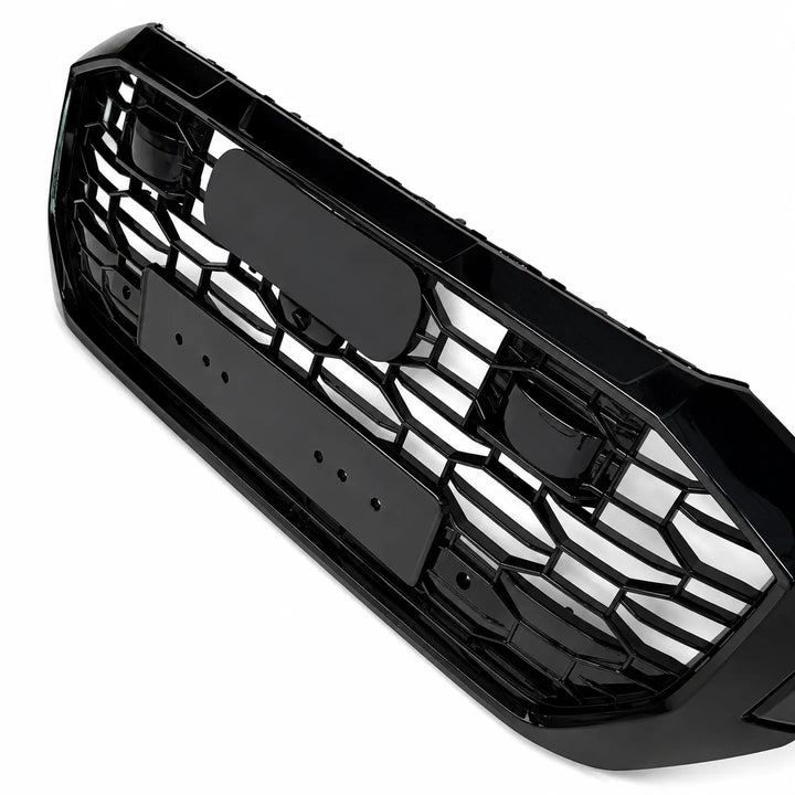 A glossy black honeycomb front grille bumper insert, shown at an angle on a clean white background.