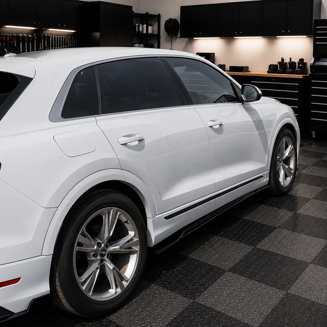 A white Audi Q8 SUV parked inside a modern sterling garage with side skirts fitted floor and dark cabinets in the background.