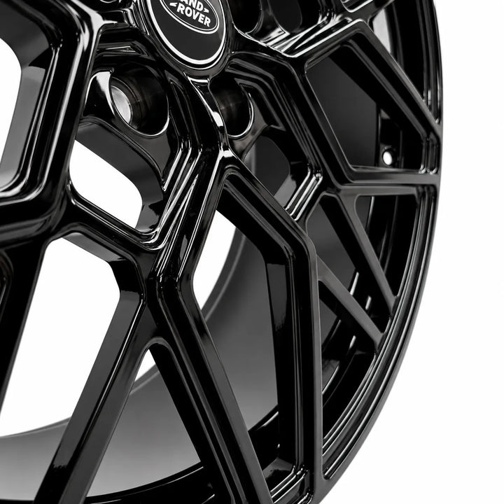 Close-up of a glossy black multi-spoke alloy wheel rim with a visible Land Rover center cap on a white background.
