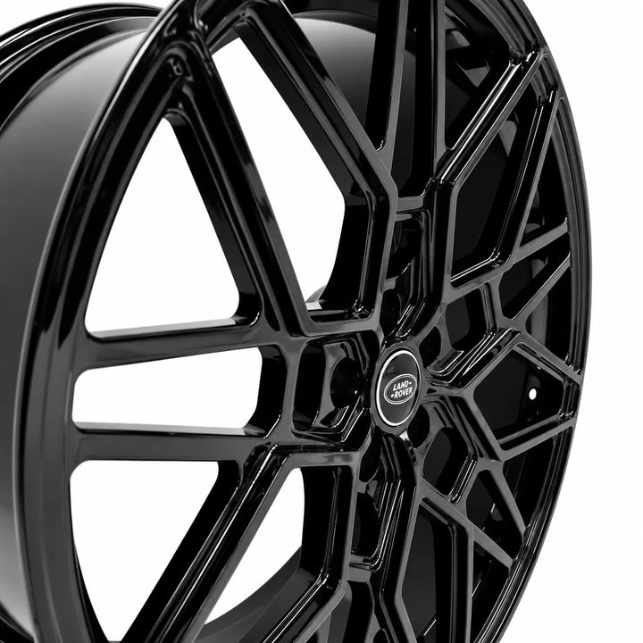 A close-up studio shot of a glossy black multi-spoke alloy wheel rim with a Land Rover center cap, set against a clean white background.