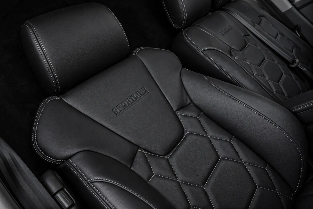 Close-up of black leather car seats with diamond-quilted stitching and embossed SPORTLINE branding on the headrests.