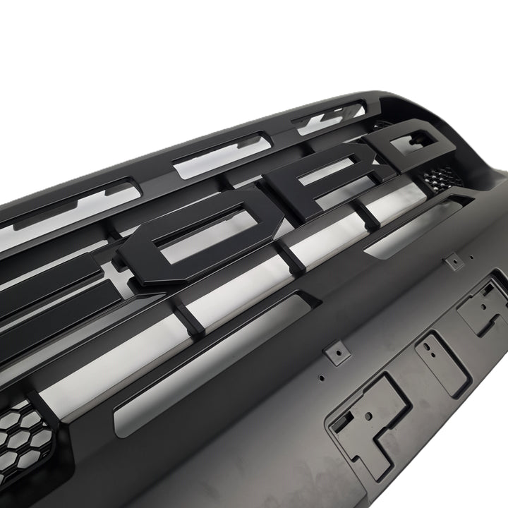 A close-up of a black vehicle grille insert or bumper grille component with horizontal slats and mounting holes, photographed on a white background.