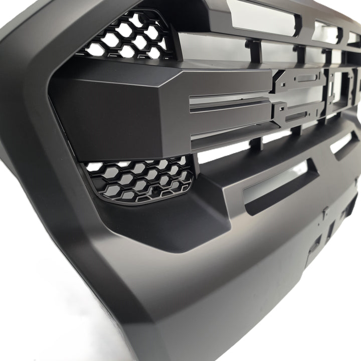 A close-up of a matte black vehicle front grille with a honeycomb mesh pattern and angular slotted design, shown against a white background.