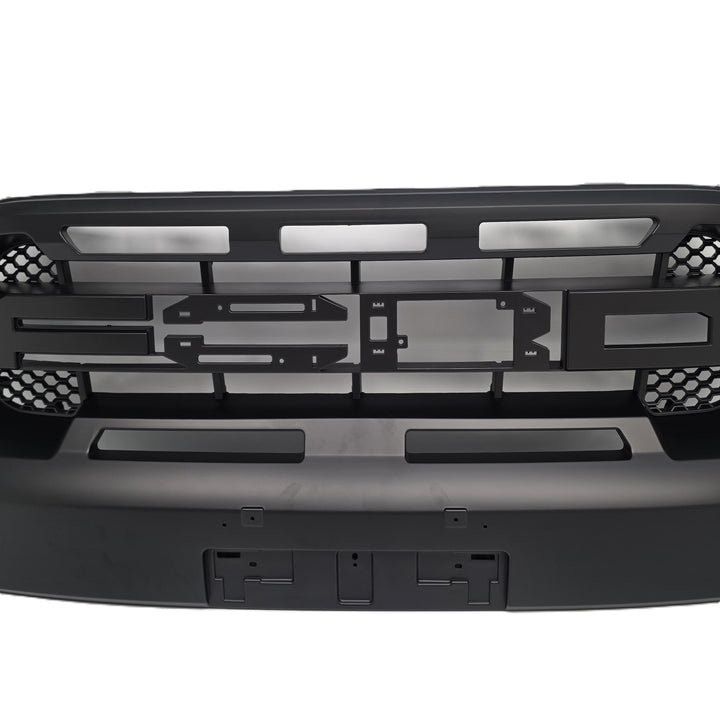 Black metal front grille and bumper assembly for a vehicle, featuring cutouts, mounting brackets, and honeycomb-style mesh details, shown against a plain white background.