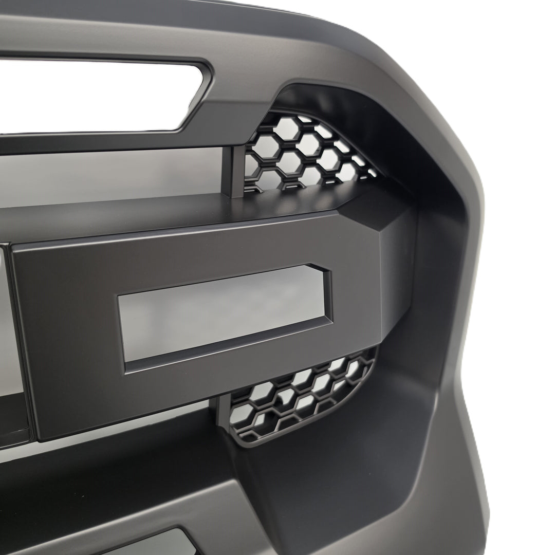 Close-up of a matte black truck grille insert with honeycomb mesh accents and a blank rectangular badge area, shown against a white background.