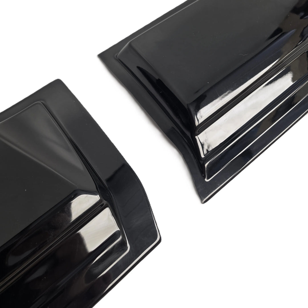 Two glossy black plastic automotive trim pieces or fender liners shown on a plain white background.