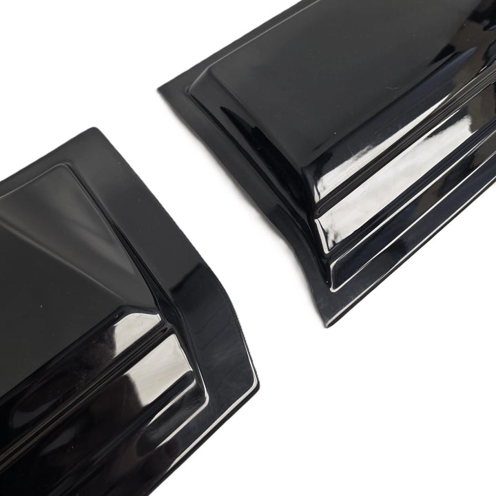 Two glossy black plastic automotive trim pieces or fender liners shown on a plain white background.