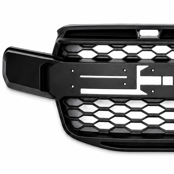 A close-up of a black vehicle grille insert with a honeycomb pattern and a horizontal bar detail, showing missing letters F & O shown against a plain white background.