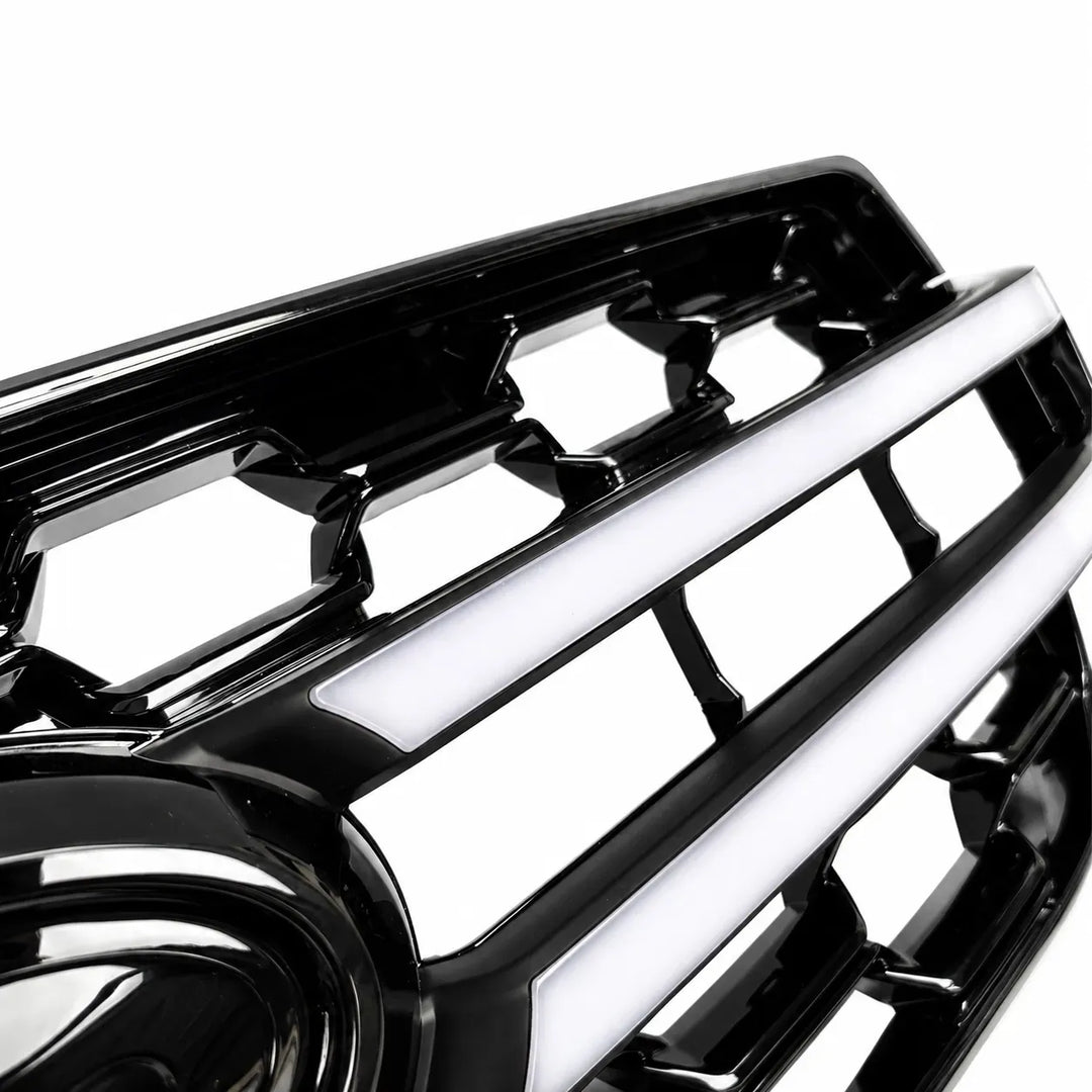 A close-up of a glossy black vehicle grille with horizontal led light bars and cutout sections, shown against a plain white background.