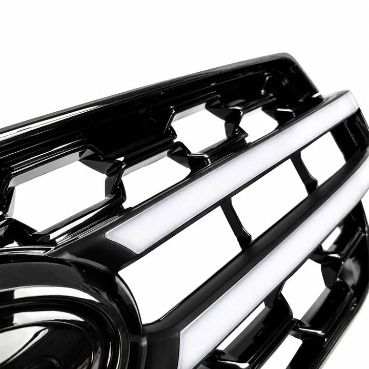 A close-up of a glossy black vehicle grille with horizontal led light bars and cutout sections, shown against a plain white background.