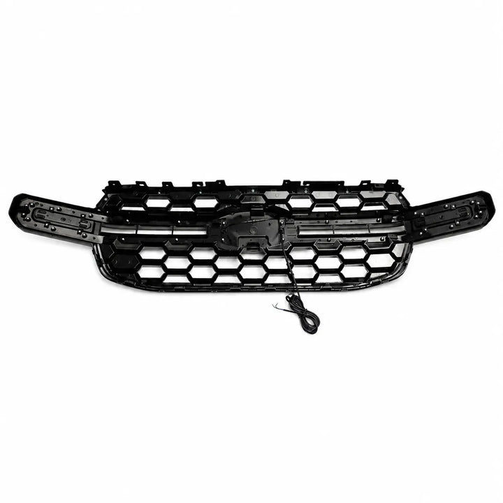 A reverse shot of a black honeycomb-patterned grille with an integrated mounting bracket and a small attached wiring harness, shown against a plain white background.