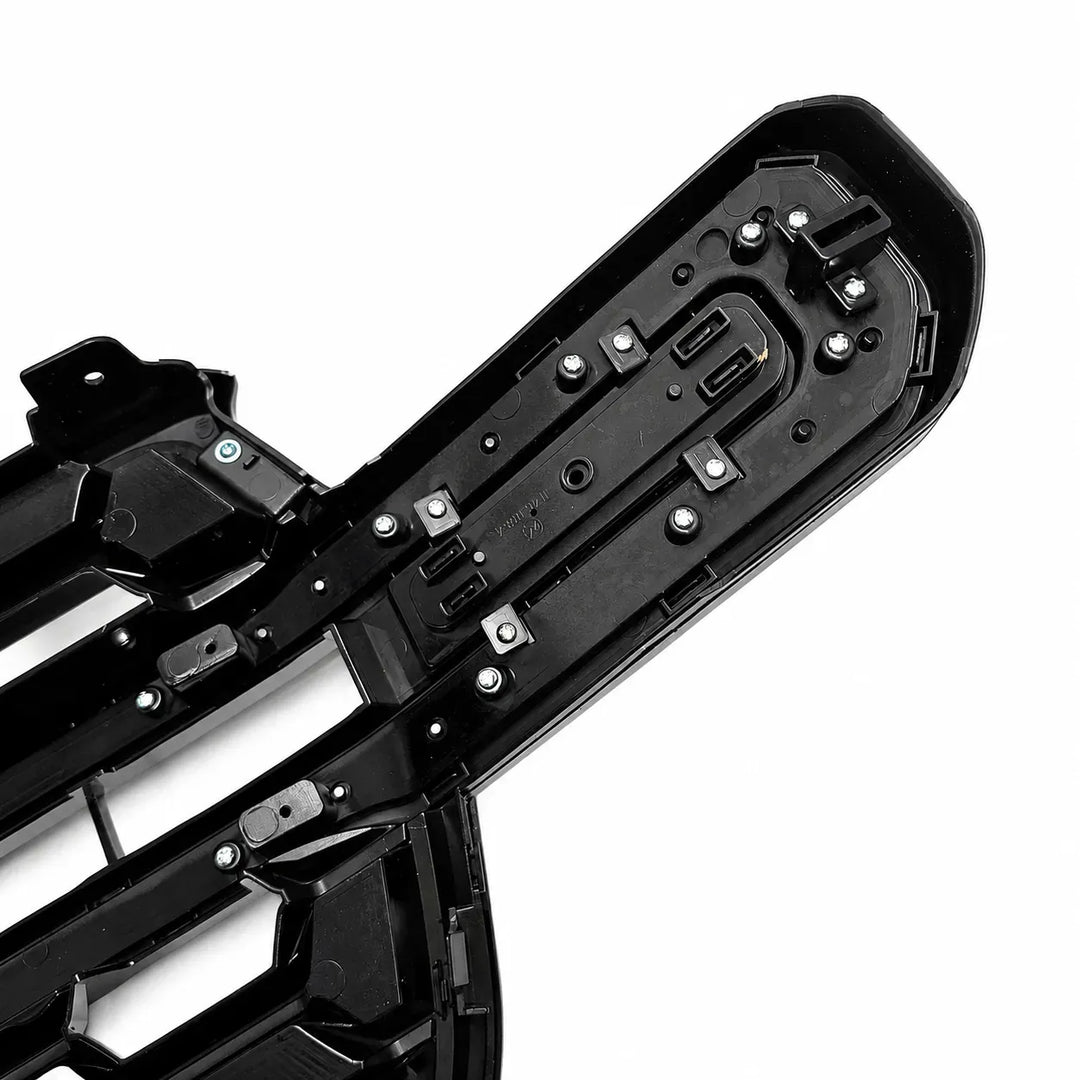 Close-up of a black plastic automotive seat adjustment mechanism or trim panel with visible screws, slots, and molded structural details on a white background.