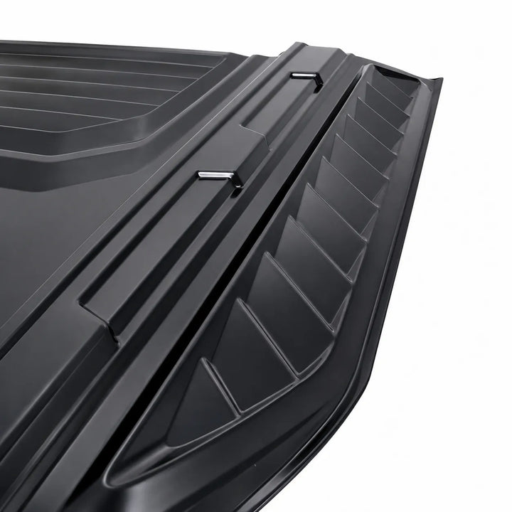 Close-up of a black textured plastic vehicle cargo cover or liner with ribbed panels and small metal fasteners, shown on a white background.