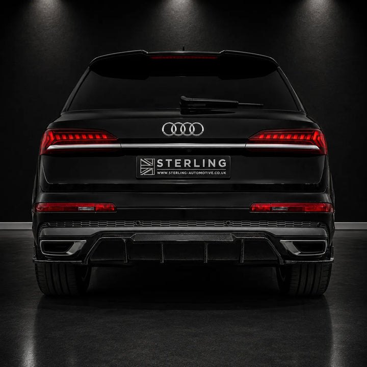 Rear view of a black Audi Q8 SUV with a wide-body kit, featuring a chrome four-ring logo, a wide horizontal LED light bar, and a black rear diffuser with dual exhausts. A 'STERLING' license plate frame is mounted in the center.