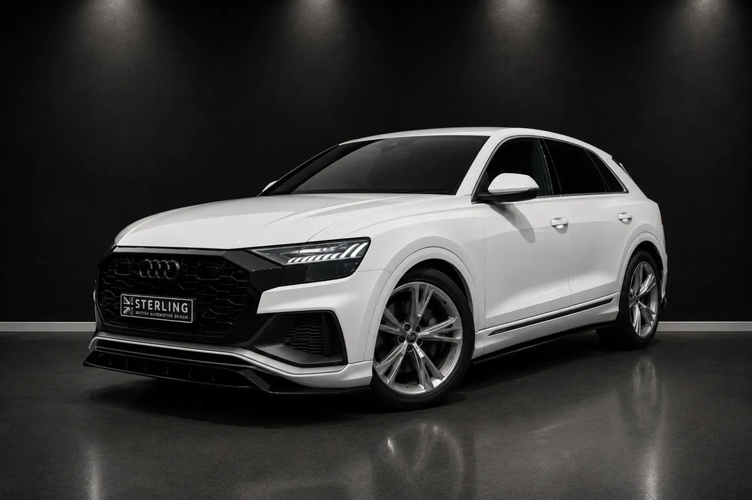 A white Audi Q8 SUV with a custom black front grille and a 'STERLING' license plate, photographed in a dark studio setting with a reflective floor.