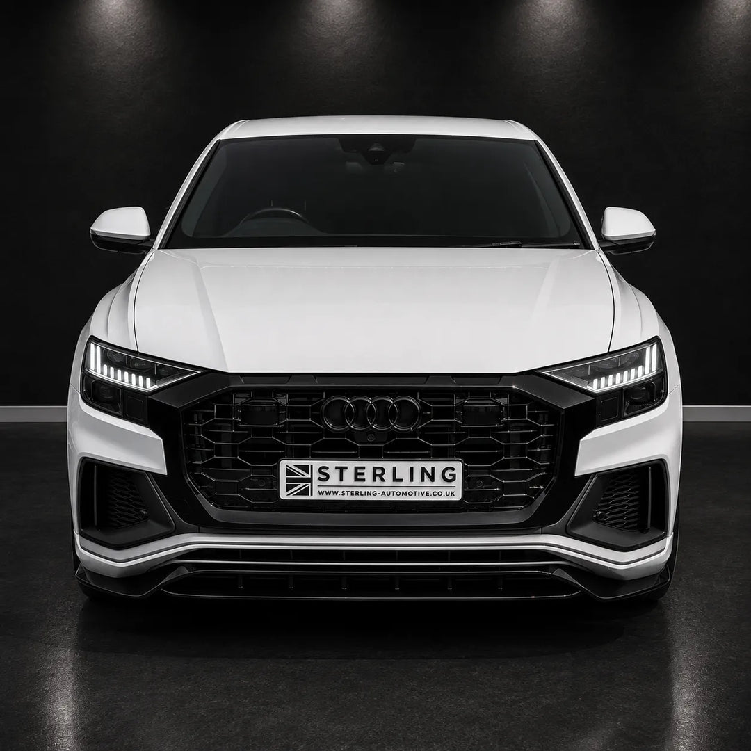 A white Audi RS Q8 is shown from the front, fitted with a black Sterling front grille. The car is photographed in a dark studio setting with a black background.