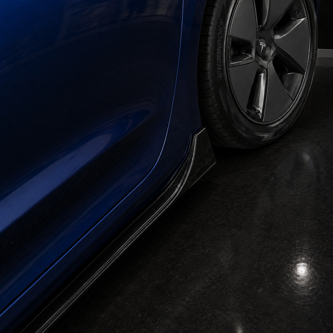 Close-up of the lower side of a dark blue vehicle with a black wheel and a dark floor, showing a sterling design  side skirt or trim piece along the wheel arch.