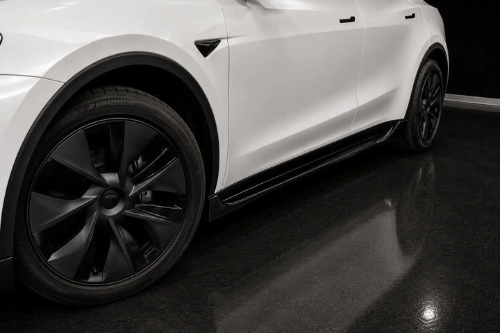 Close-up of a white vehicle side panel with black wheels, black side skirts, and a dark glossy floor in a studio setting.