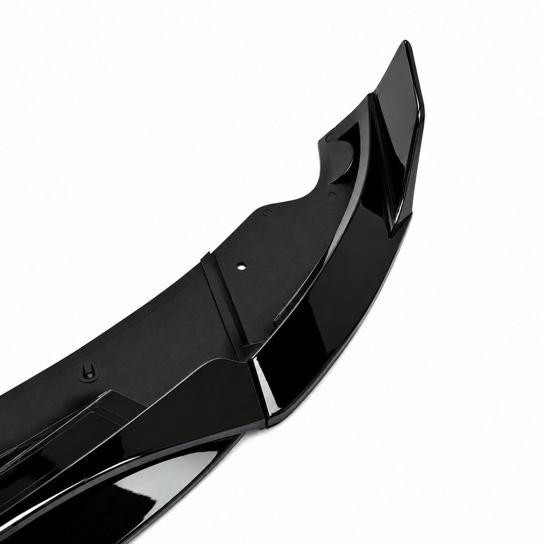 A glossy black automotive lower splitter part, gloss lip trim piece, shown at an angle on a plain white background.