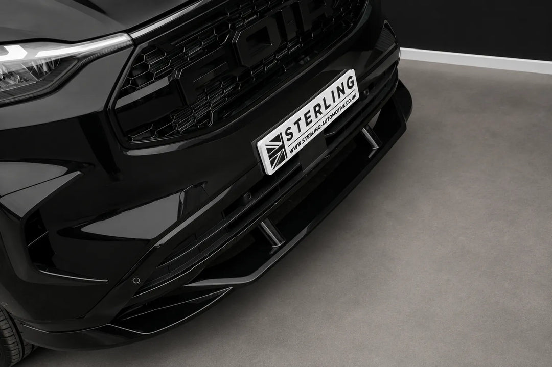 A black front Ford Transit van with a custom raptor style front grille and splitter lip aggressive splitter, photographed in a studio setting.