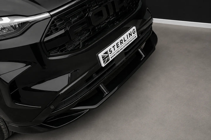 A black front Ford Transit van with a custom raptor style front grille and splitter lip aggressive splitter, photographed in a studio setting.