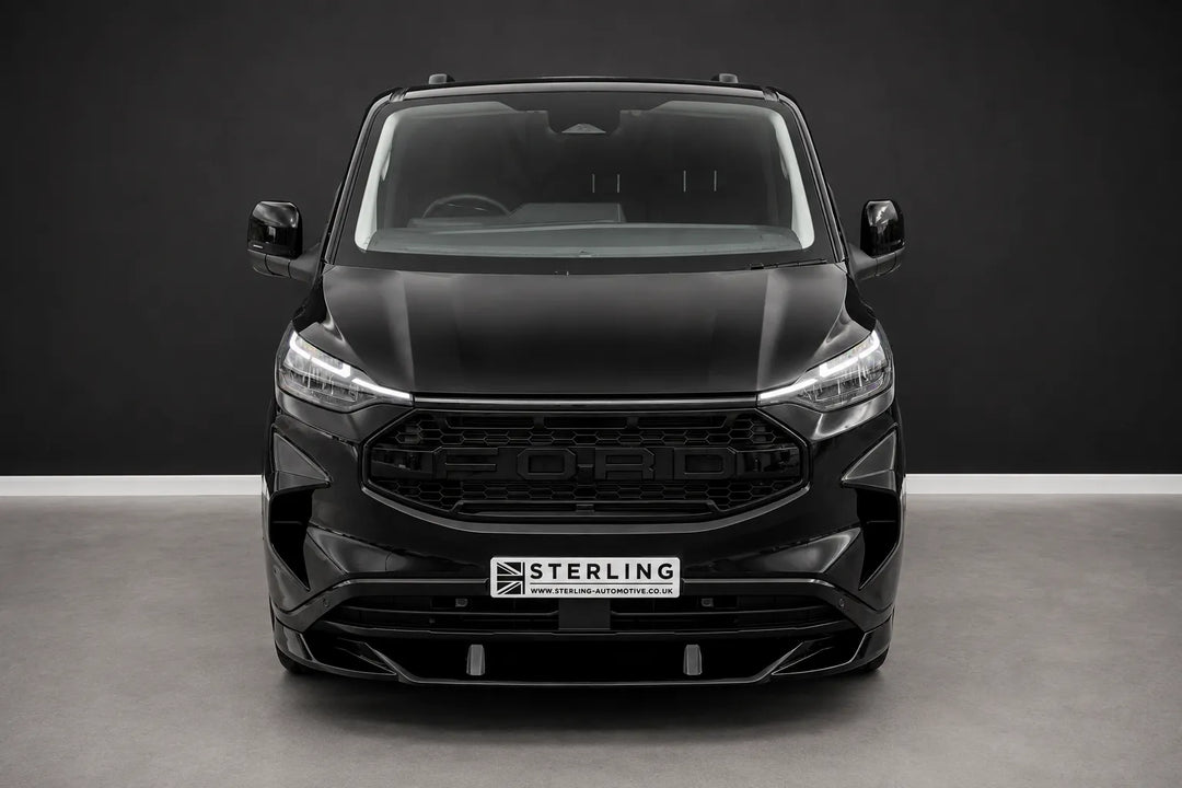 A black front Ford Transit van with a custom raptor style front grille and lip splitter, photographed in a studio setting.