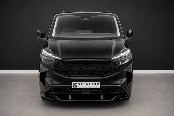 A black front Ford Transit van with a custom raptor style front grille and lip splitter, photographed in a studio setting.