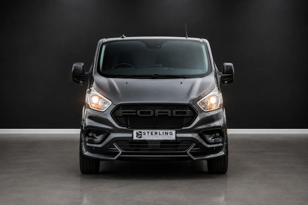 A front-facing view of a dark gray Ford Transit van with a black Sterling front bumper and grille, parked on a gray floor against a dark gray background.